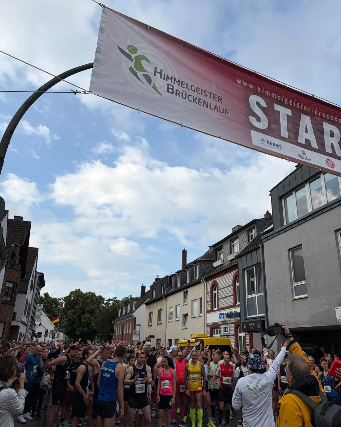Startbereich des Brückenlaufs in Himmelgeist: Läuferinnen und Läufer warten unter dem Startbanner auf den Startschuss.